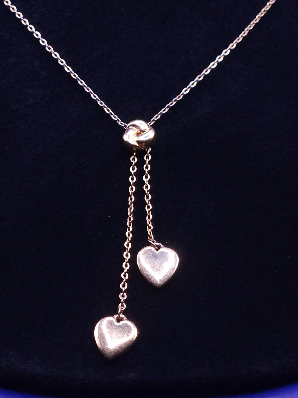 gold-colored heart lariat Style necklace features two dangling heart pendants